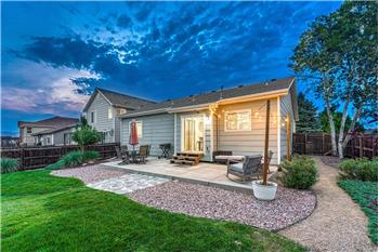 Sunset view of the backyard patio and grass areas with trees and shrubs.