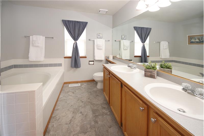 Master bathroom with window, double sink vanity, medicine cabinet, soaking tub, and separate shower