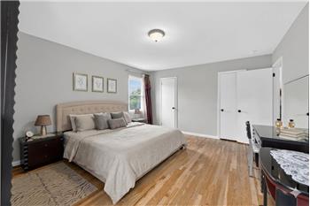 Bedroom featuring wood-finish flooring, light grey walls, and a recessed window with natural light
