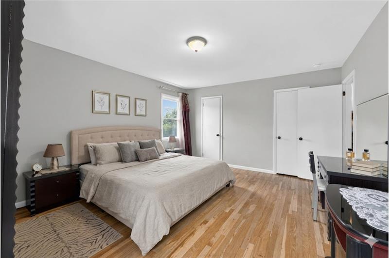 Bedroom featuring wood-finish flooring, light grey walls, and a recessed window with natural light