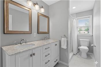 Bathroom featuring a double vanity with stone countertop, dual undermount sinks, and framed mirrors