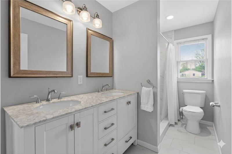 Bathroom featuring a double vanity with stone countertop, dual undermount sinks, and framed mirrors
