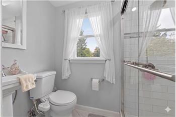 Bathroom featuring a glass-enclosed shower with white subway tile, a white pedestal sink