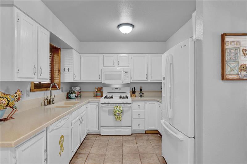 White appliances include a dishwasher, French door refrigerator, gas range oven, and built-in microwave oven