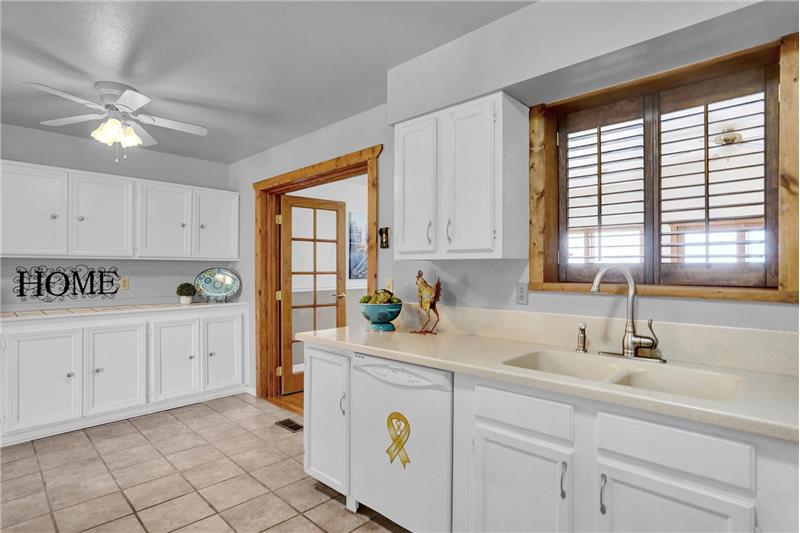 Beautiful Eat-In Kitchen w/tile floors, white cabinets w/Corian counters, a lighted ceiling fan, & French doors into the DR & FR