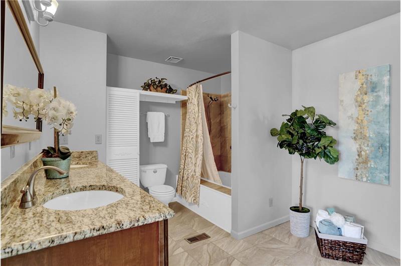 Full upper level Master Bathroom with tile floor, granite vanity with dual sinks, framed mirror, and tiled tub/shower