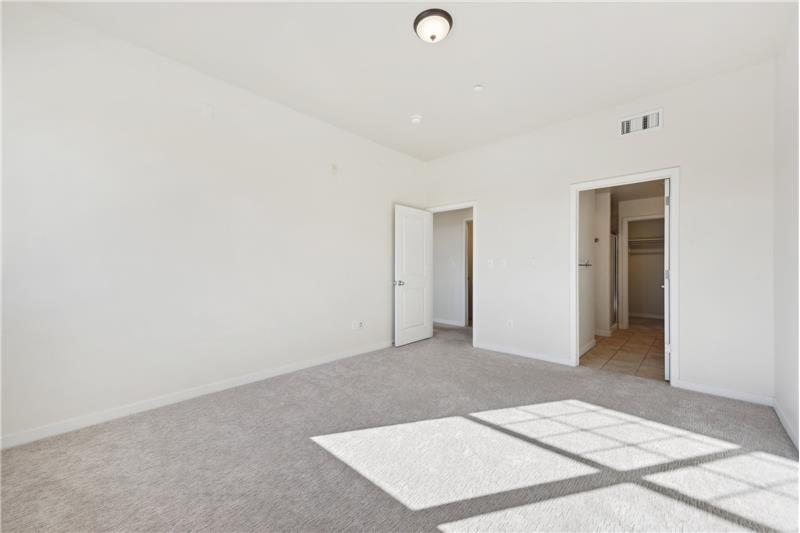 12x15 primary bedroom, showing door to hallway and opening to the ensuite bathroom with walk-in closet