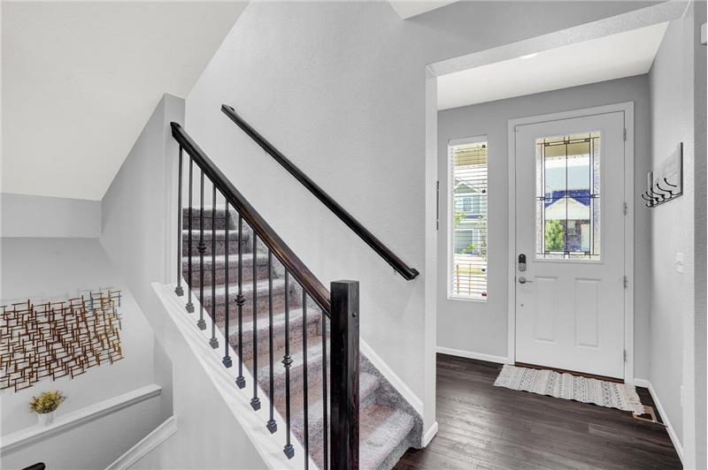 Front Entry with textured luxury vinyl plank floors and stairs with iron spindles to the upper level