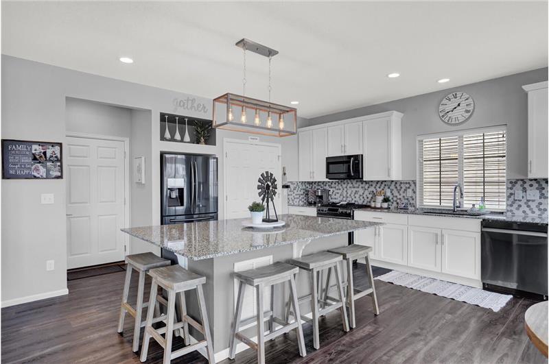 The Kitchen features an island with counter bar and light fixture, walk-in pantry, and cabinets with granite countertops and