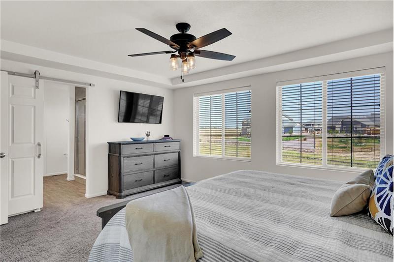Upper-level Master Bedroom with views to the backyard and open space from large view windows with blinds