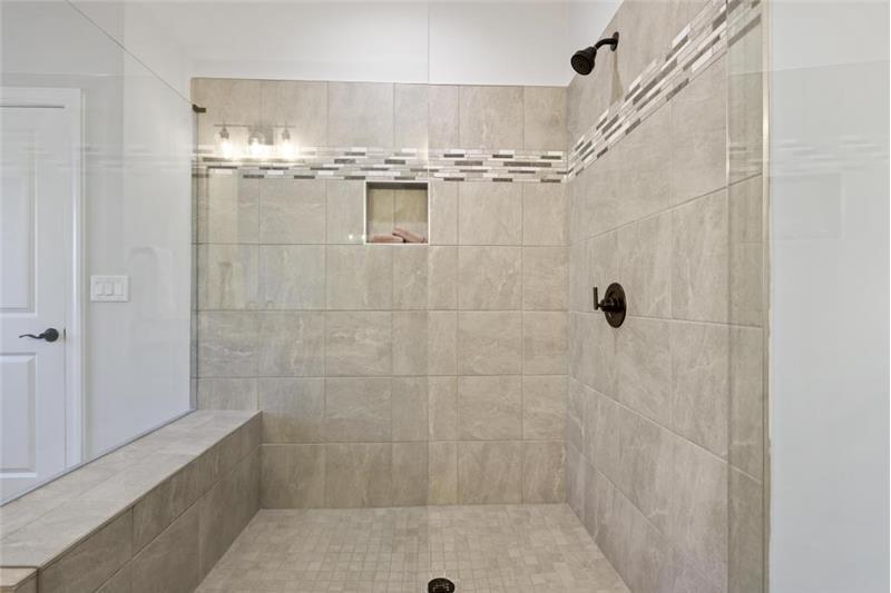 Huge walk-in tiled shower with sitting area