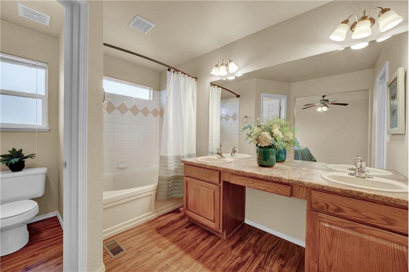 MBR incl new luxury vinyl plank wood-look floors, a dual sink vanity, tiled tub/shower, and walk-in closet