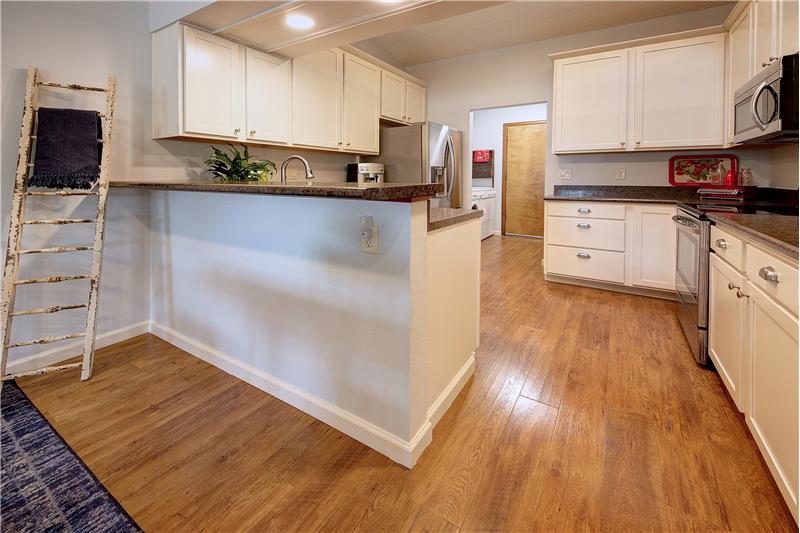 Updates to this beautiful and functional kitchen include cabinetry, counter tops, stainless steel appliances, and flooring