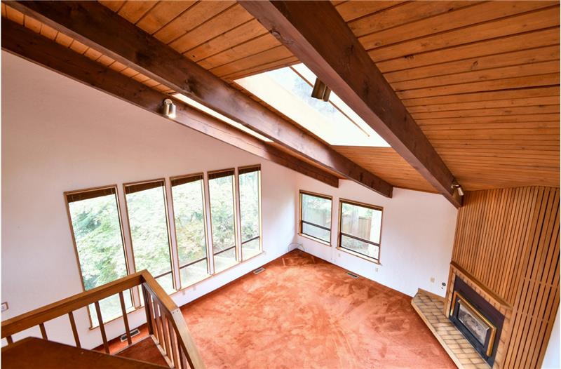 Another view of the architecture with the beams, vaulted ceilings, fireplace and windows!  Truly a unique custom home!