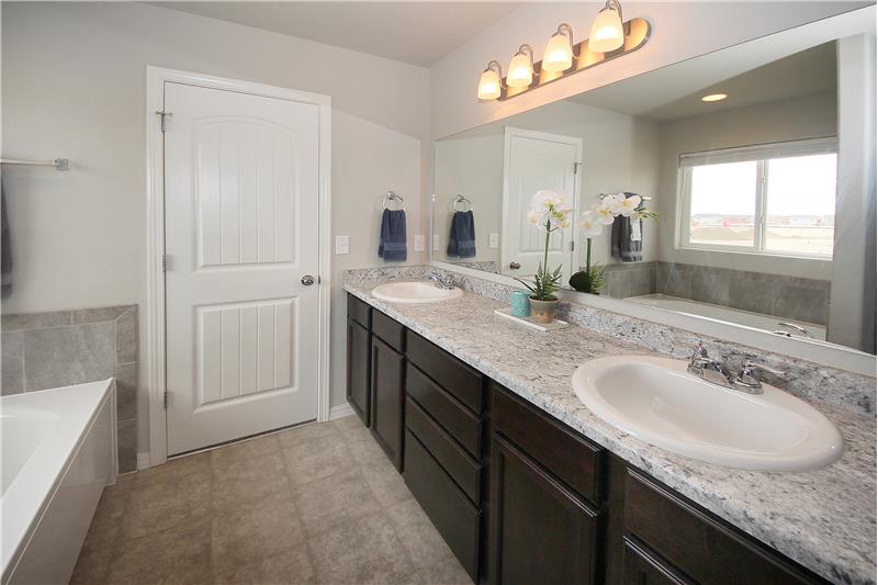 Master bathroom with double sinks, comfort height vanity, soaking tub, and large shower