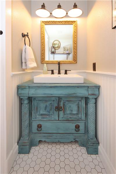 Updated Powder Bathroom off the Entry w/tile floor, decorative vanity, shiplap wall w/built-in shelf, & wainscoting