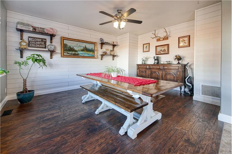The Family Room (currently used as a Dining Room) features a shiplap wall, lighted ceiling fan, & large window