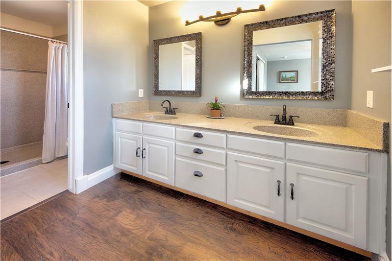 The Master Bathroom offers tile floors, a double sink vanity, framed mirrors, an updated light fixture, & walk-in shower