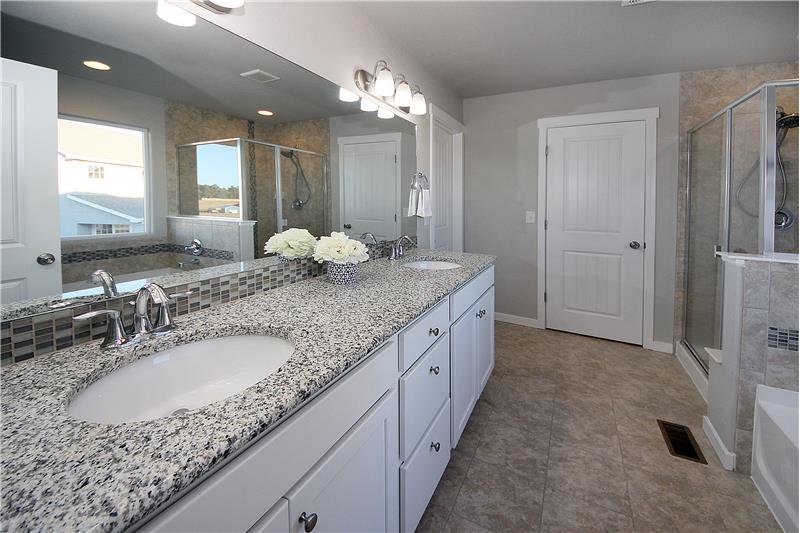 Master bathroom with double sinks, granite, soaking tub, and large shower
