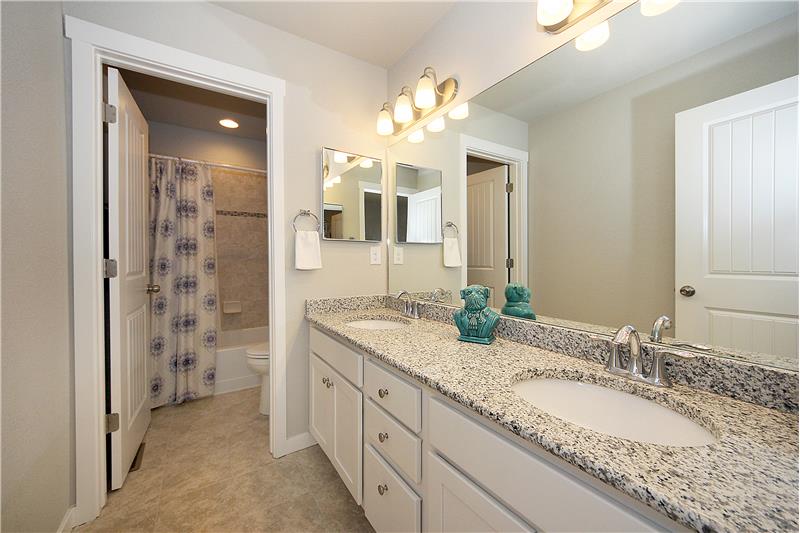 Full bath with granite, tile, medicine cabinets, and double sinks on upper level