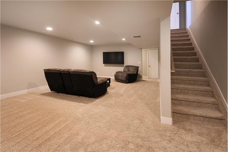 Bonus rec room in basement with recessed lighting and door at the top of the stairs