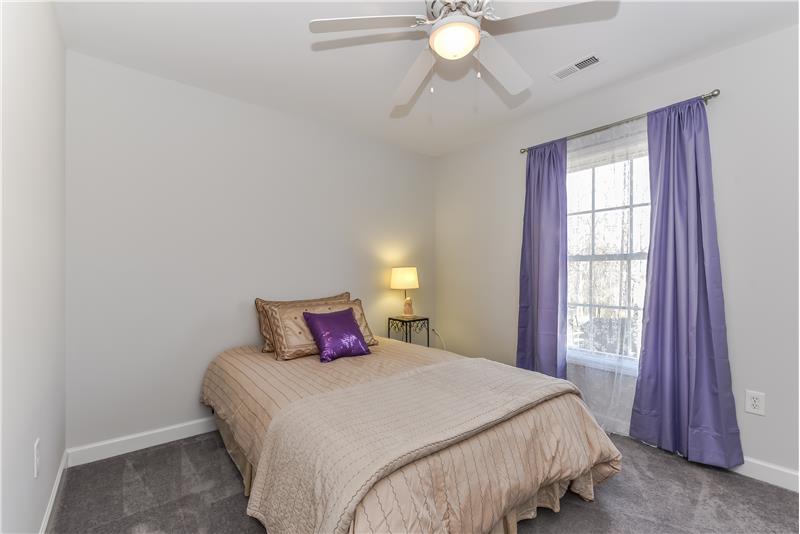 One of two secondary bedrooms on main floor of home with walk-in closet and ceiling fan.