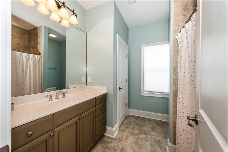 En-suite bathroom on second floor of home features tile floor, expansive counter-top, linen closet, window, tub/shower.