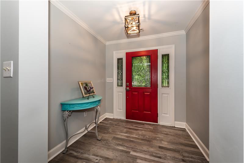 Foyer with luxury vinyl plank flooring and crown molding welcomes you.