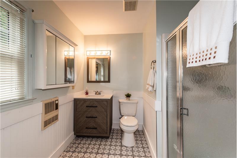 In-law suite bathroom features new vanity, step-in shower, new toilet, new tile floors, bead board accent.