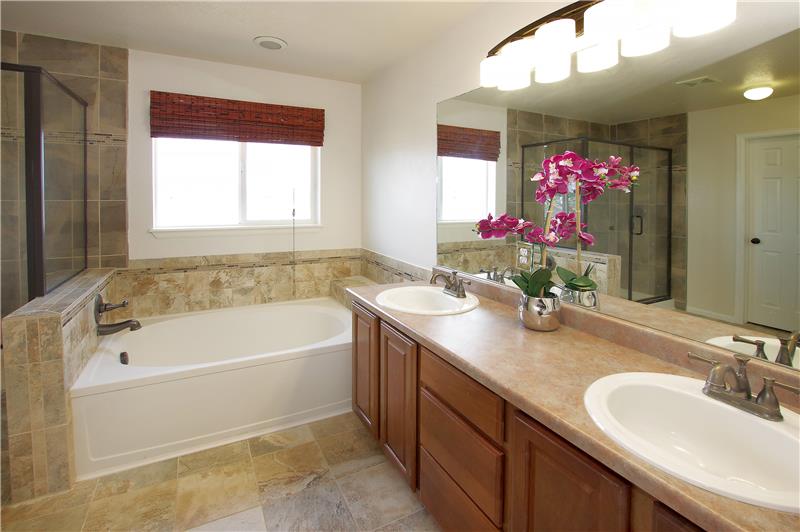Updated master bathroom with tile, double sink vanity, soaking tub, and separate shower