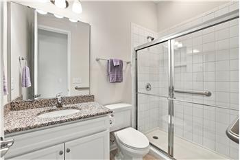 Main floor bathroom between the home's two front bedrooms with extended, tiled shower, granite counter, grab bars.