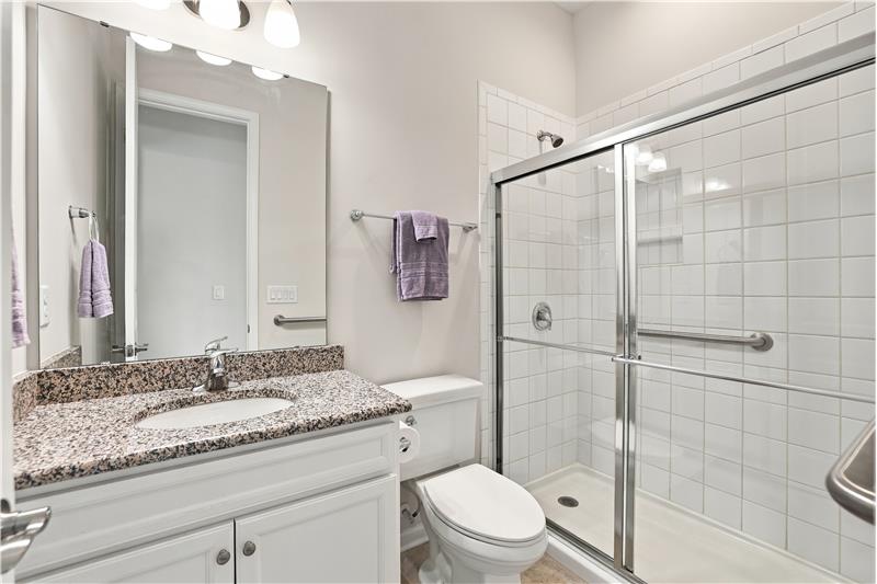 Main floor bathroom between the home's two front bedrooms with extended, tiled shower, granite counter, grab bars.