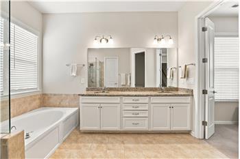 Primary bath: granite vanity counter, crisp white cabinetry, tile flooring and surround, walk-in closet.