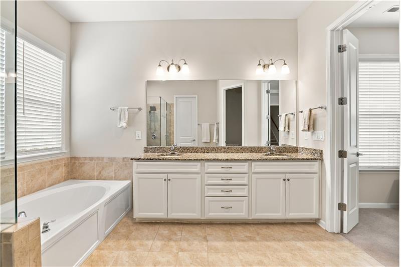 Primary bath: granite vanity counter, crisp white cabinetry, tile flooring and surround, walk-in closet.