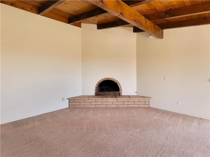 Gas assisted fireplace with stone hearth is absolutely fitting with the exposed beam ceiling!