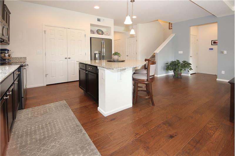 There are pendant lights over the large, curved island w/counter bar, & additional cabinets for lots of storage & work space