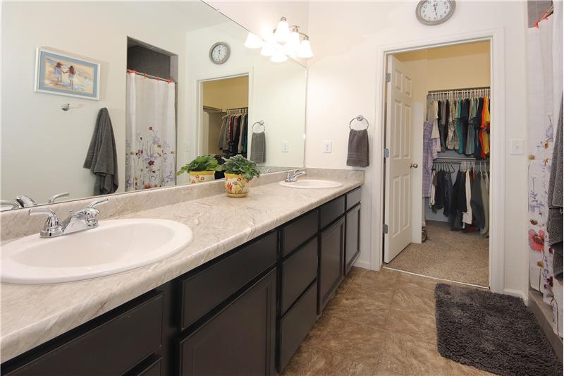The Master 4pc Spa Bathroom features a vinyl floor, dual sink vanity, tiled shower, and walk-in closet