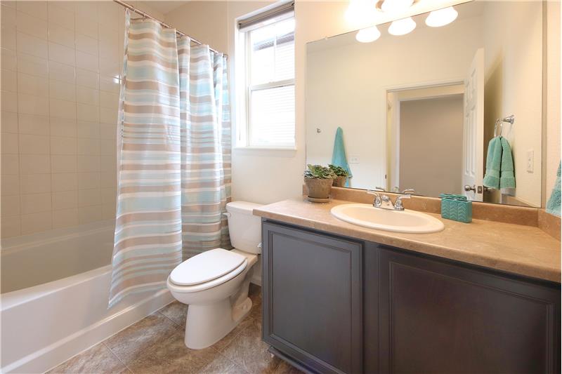 The main level hall Bath includes a vinyl floor, vanity, and tiled tub shower
