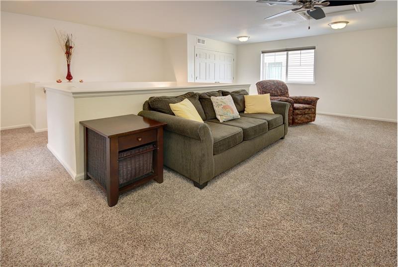 The upper-level loft features neutral carpet and ceiling fan