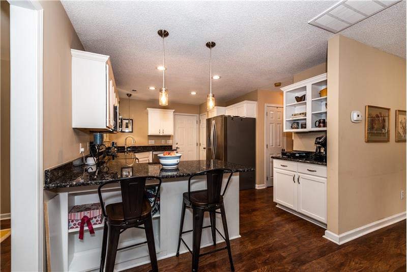 Kitchen features recessed lighting, updated pendant lights, shelves to store cookbooks, pantry.