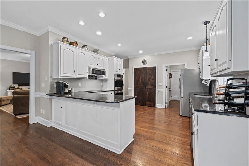 Cook's kitchen has granite counters, newer stainless steel appliances, pantry with barn-style doors.