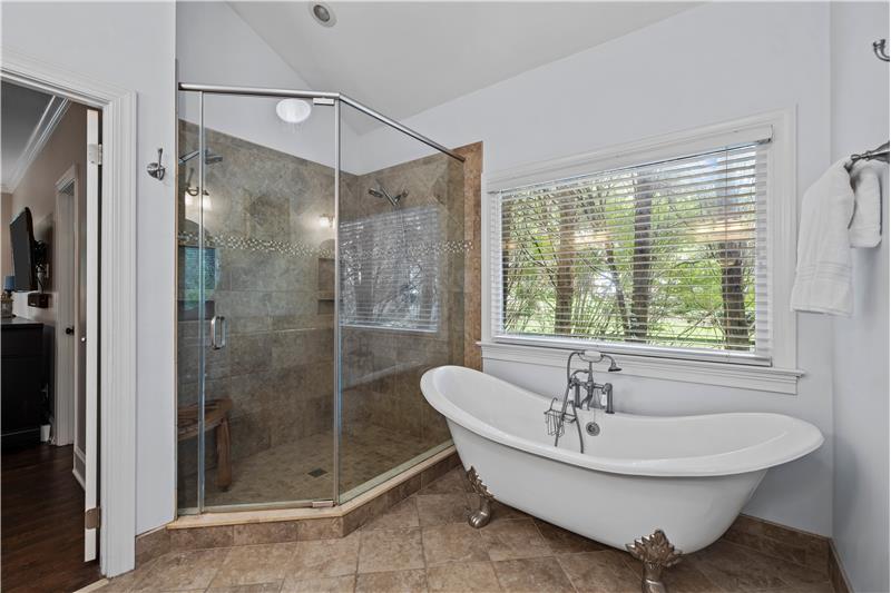 Spa-inspired owner's bathroom with large tiled shower, stand-alone, clawfoot tub.