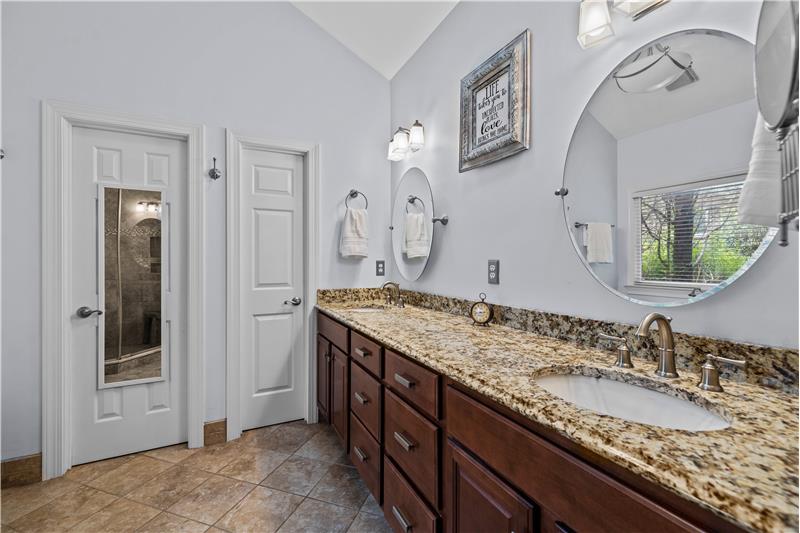 Owner's bathroom: expansive, dual-sink vanity with granite; private WC, linen closet, vaulted ceiling, tile floors.