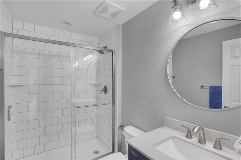 Basement Shower Bathroom with vanity, mirror, and tiled shower
