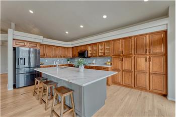 Beautiful large island with quartz countertop, breakfast bar, and wall of wood cabinetry.
