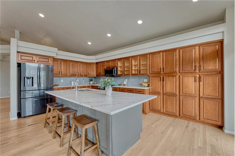 Beautiful large island with quartz countertop, breakfast bar, and wall of wood cabinetry.