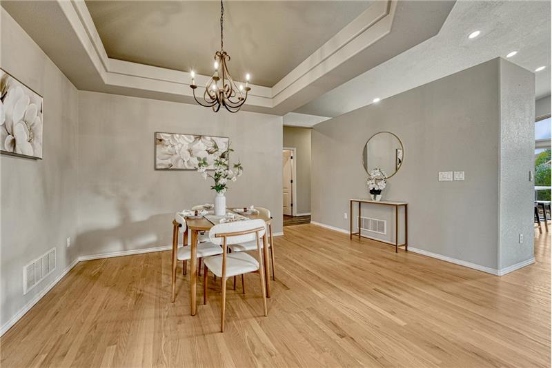 Formal Dining Area, perfect for entertaining with wood floor, tray ceiling, and attractive light fixture.