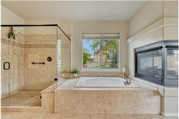 Luxurious 5-piece Primary Bathroom with 3-sided fireplace, soaking tub, and separate large tiled shower with built-in bench.