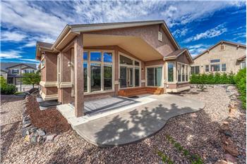 Low maintenance xeriscaped backyard yard with partially covered patio and many trees for privacy and shade.