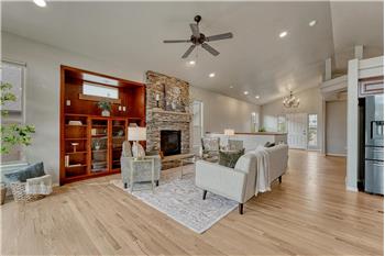 The spacious Great Room features wood flooring, a ceiling fan, custom built-ins, and a a gas fireplace.